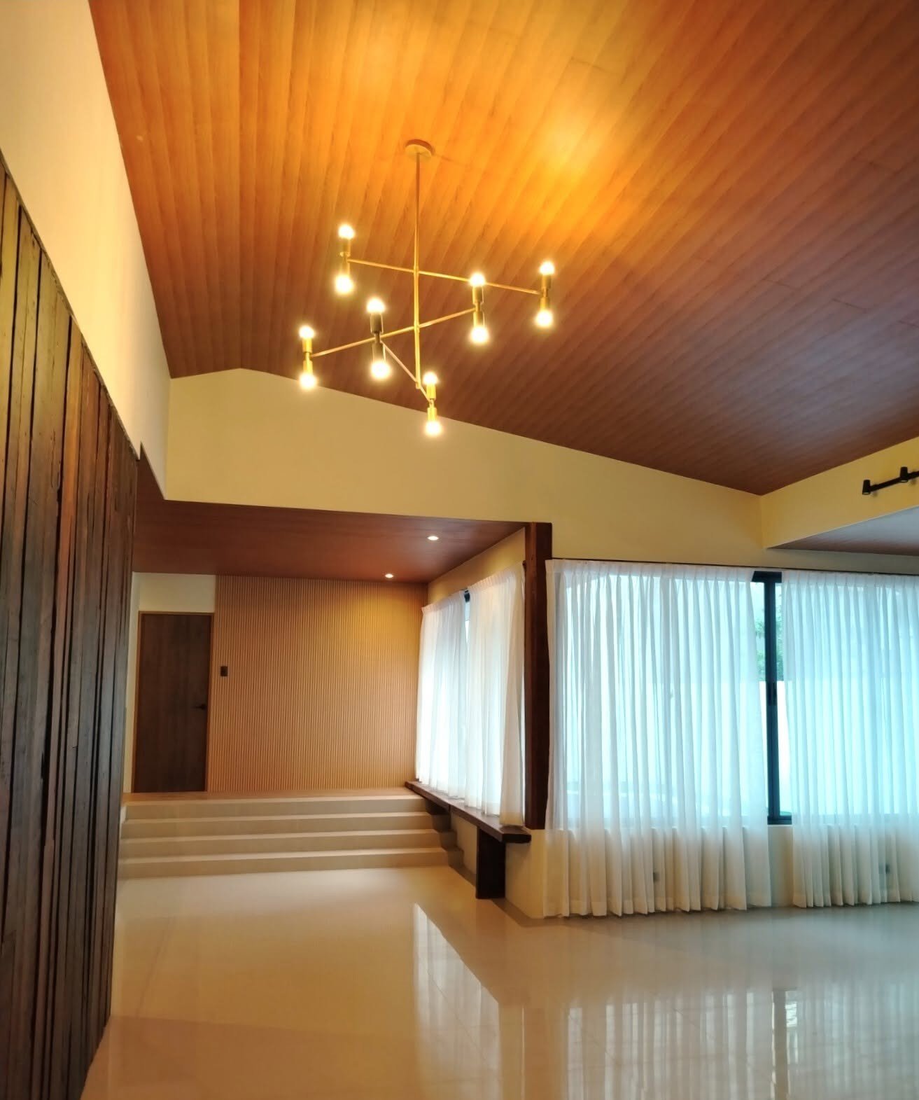 Living room with a timber ceiling, chandelier, and sheer curtains