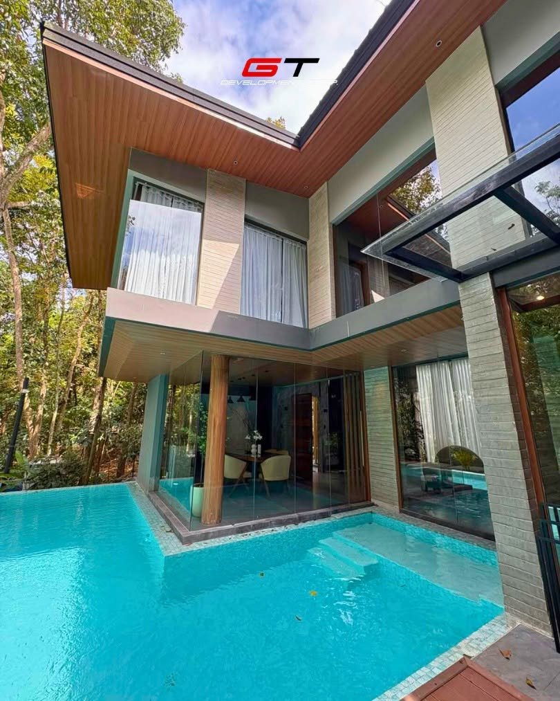 Villa with a timber roof and turquoise pool surrounded by trees